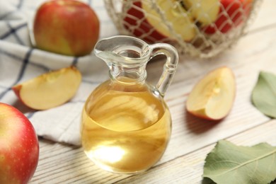 Natural apple vinegar and fresh fruits on white wooden table