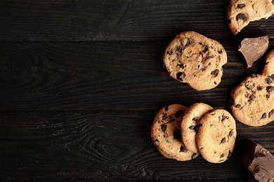 Photo of Tasty chocolate chip cookies on wooden background, top view. Space for text