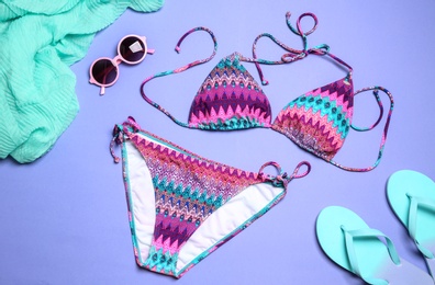 Photo of Stylish bright bikini and beach accessories on color background, above view