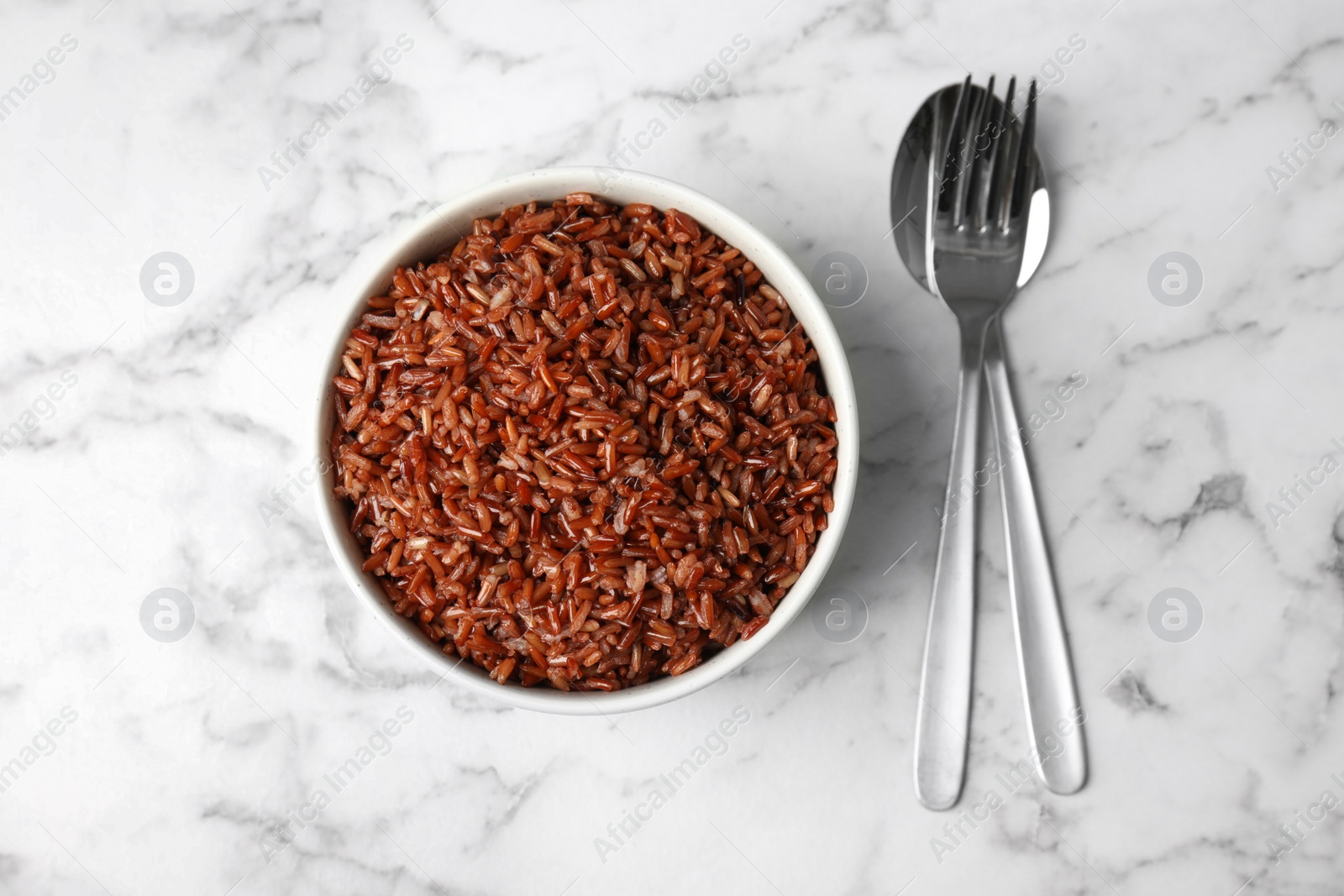 Photo of Flat lay composition with delicious cooked brown rice on white marble table