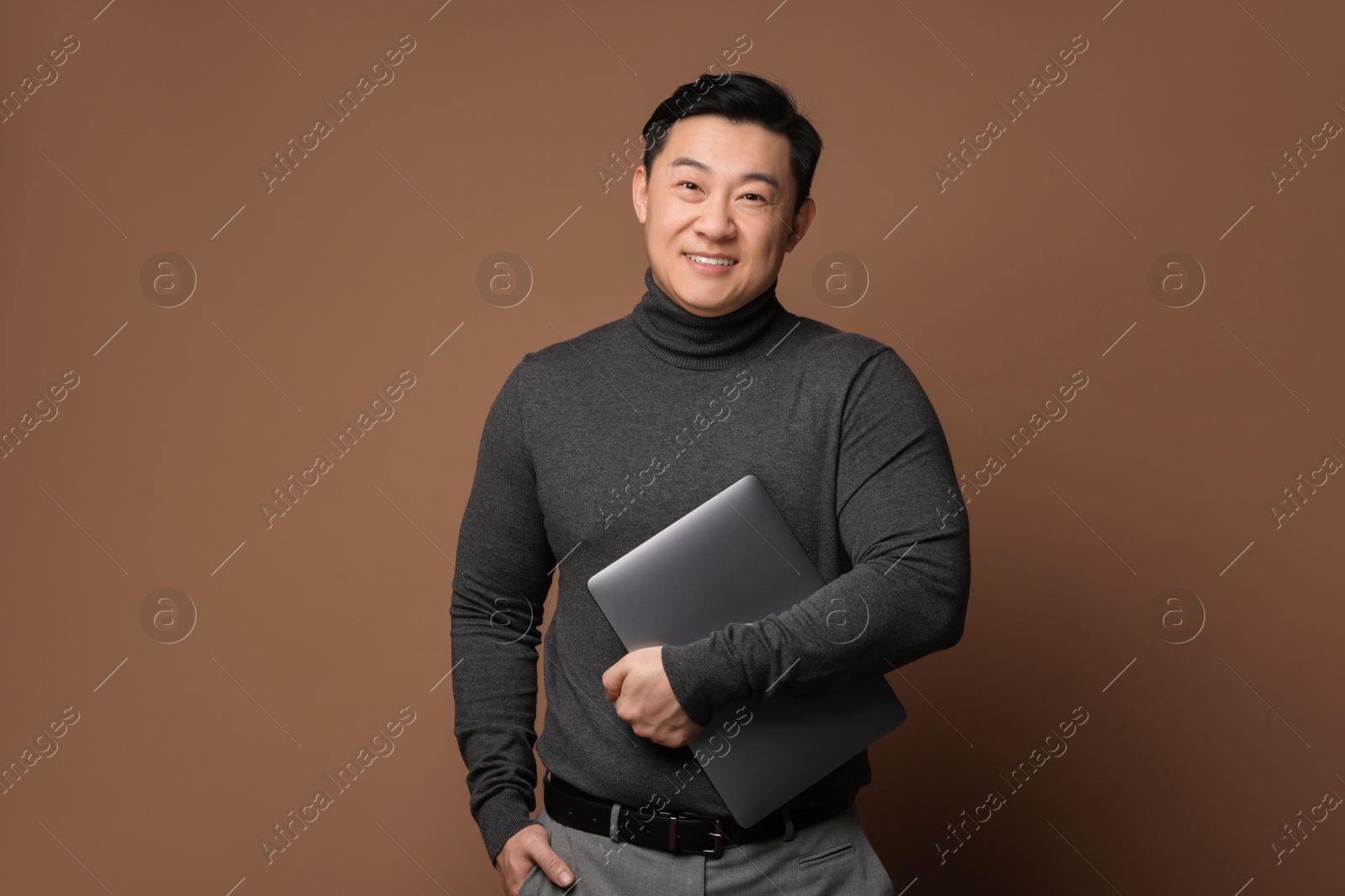 Photo of Portrait of happy man with laptop on brown background