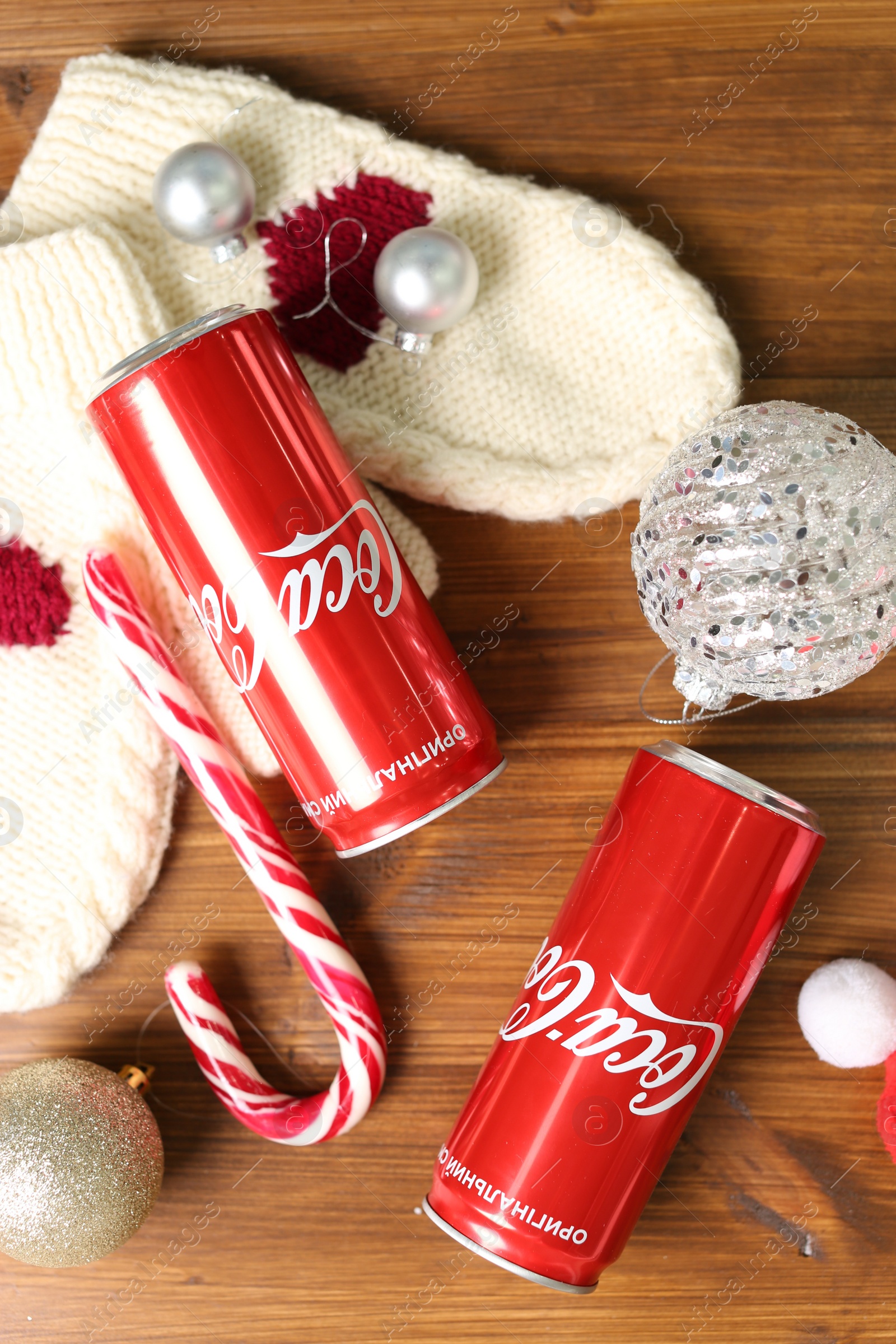 Photo of MYKOLAIV, UKRAINE - January 01, 2021: Flat lay composition with Coca-Cola cans and Christmas decorations on wooden background