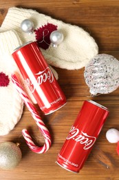 MYKOLAIV, UKRAINE - January 01, 2021: Flat lay composition with Coca-Cola cans and Christmas decorations on wooden background