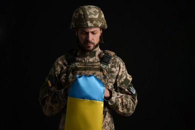 Photo of Soldier in military uniform with Ukrainian flag on black background