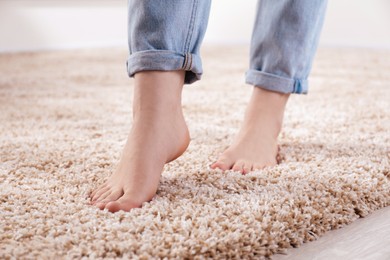 Photo of Woman standing on soft carpet at home, closeup