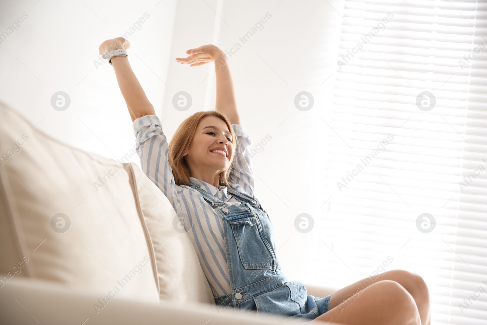 Photo of Young woman relaxing on couch near window at home