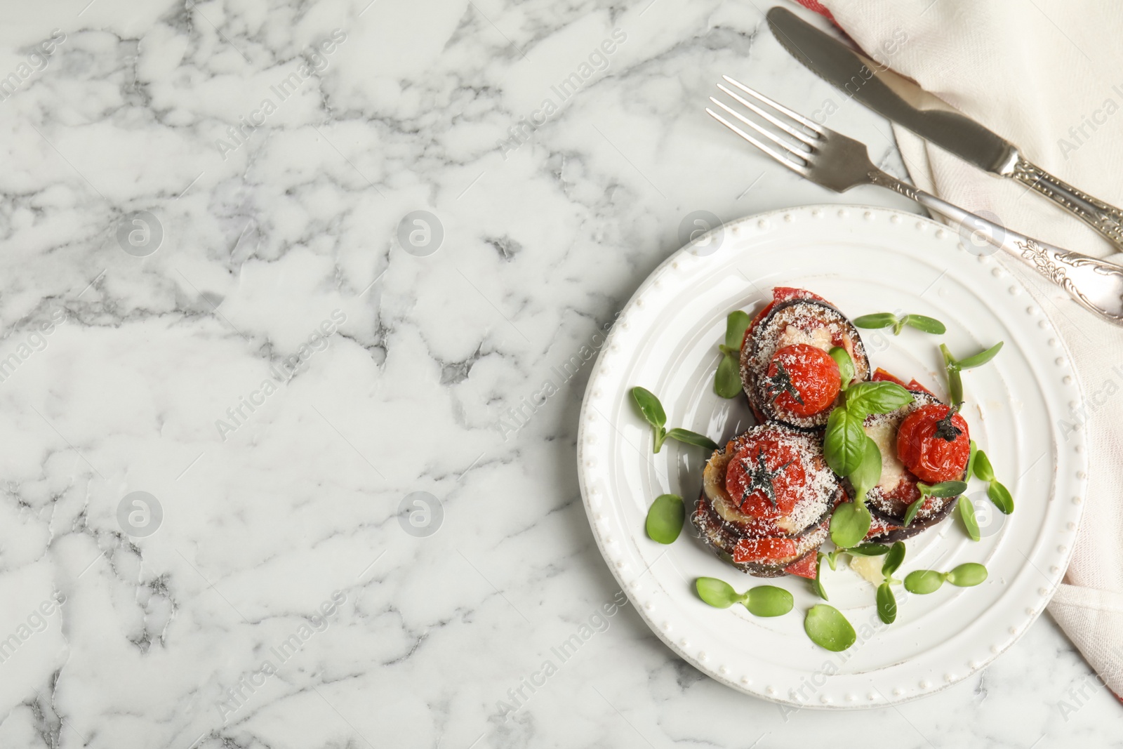 Photo of Baked eggplant with tomatoes, cheese and basil served on white marble table, flat lay. Space for text