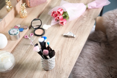 Holder with professional makeup brushes on wooden table