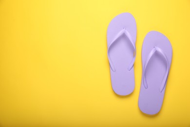 Photo of Stylish violet flip flops on yellow background, top view. Space for text