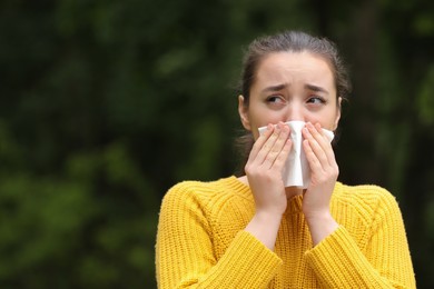 Woman suffering from seasonal spring allergy outdoors, space for text