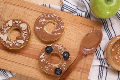 Slices of fresh apple with nut butter, blueberries and peanuts on table, flat lay