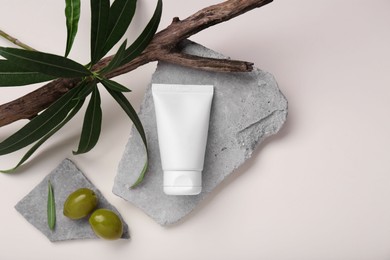 Photo of Tube of natural cream, olives, stones and branch with leaves on white background, flat lay. Space for text