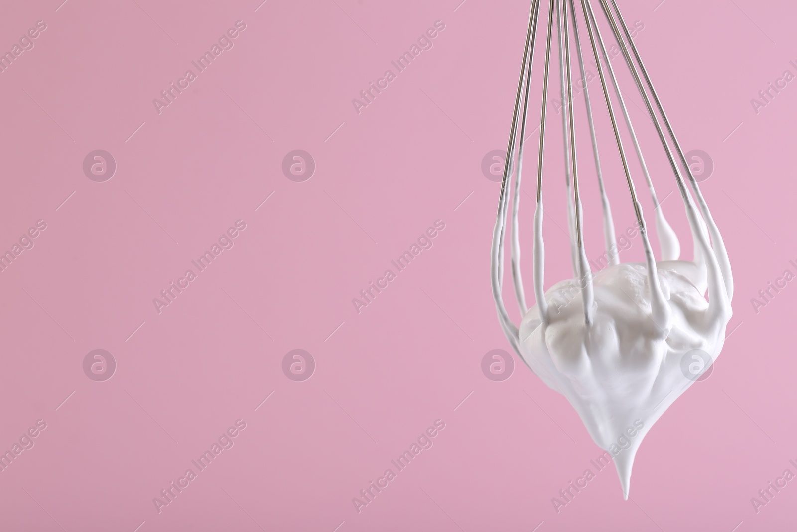 Photo of Whisk with whipped cream on pink background. Space for text