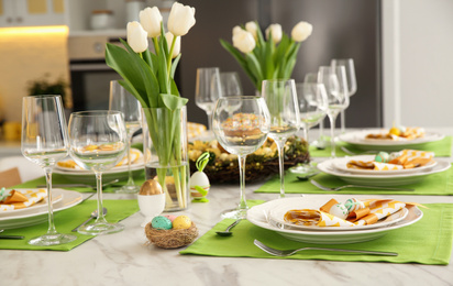 Photo of Festive Easter table setting with floral decor in kitchen
