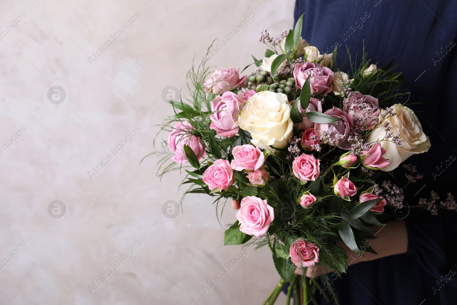 Photo of Woman with bouquet of beautiful roses on beige background, closeup. Space for text