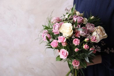 Woman with bouquet of beautiful roses on beige background, closeup. Space for text