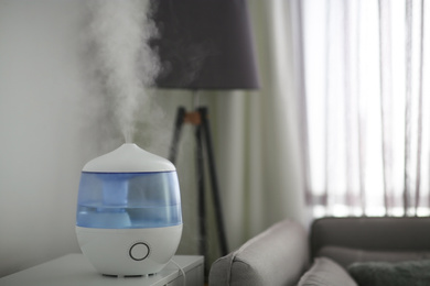 Photo of Modern air humidifier on table in living room. Space for text