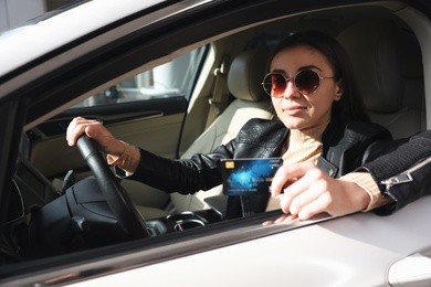 Woman sitting in car and giving credit card at gas station