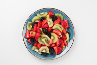 Plate of yummy fruit salad on light blue background, top view