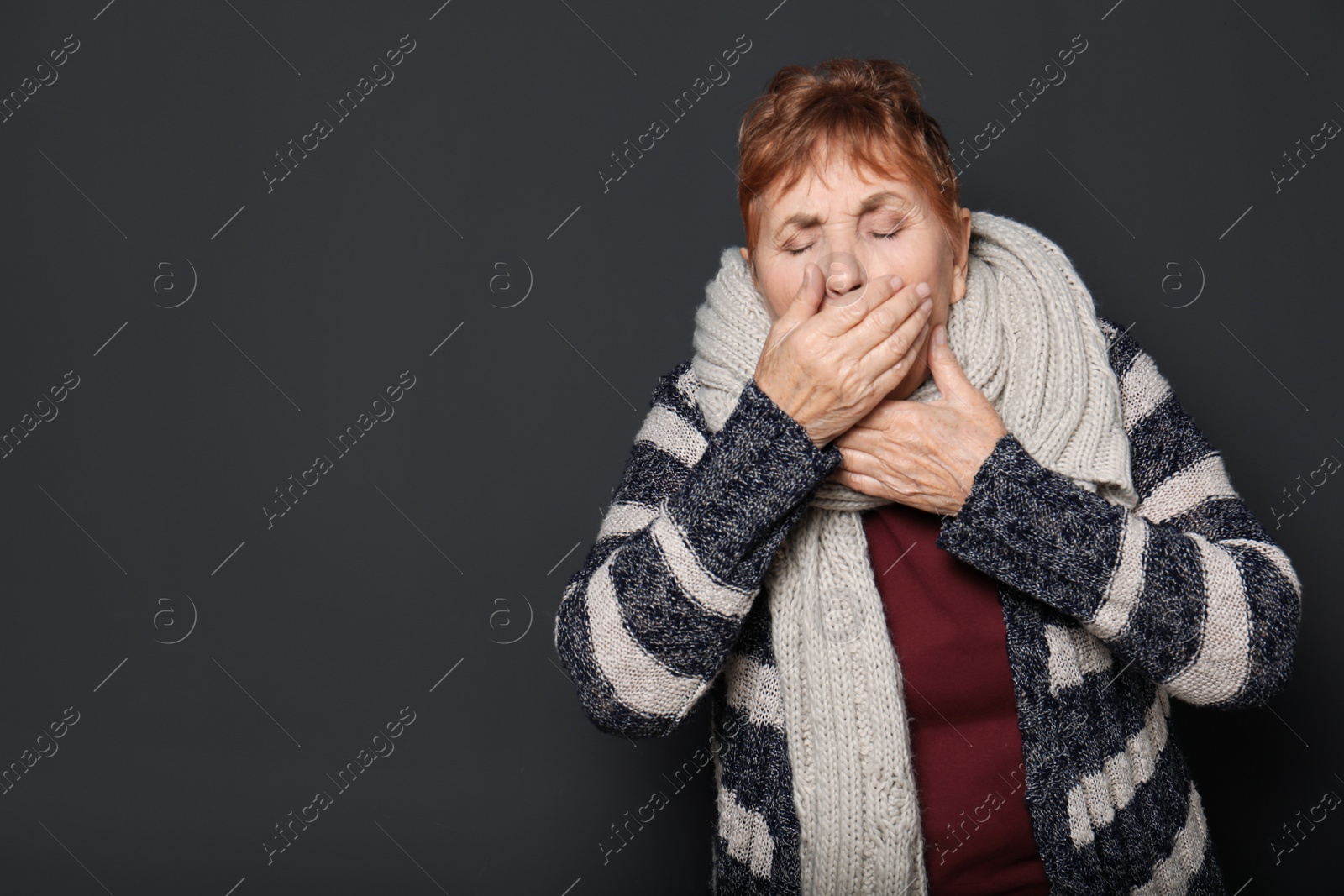 Photo of Elderly woman coughing against dark background. Space for text