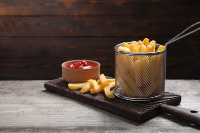 Tasty French fries and ketchup on light grey wooden table
