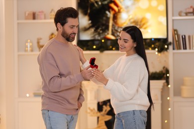Making proposal. Man with engagement ring surprising his girlfriend at home on Christmas