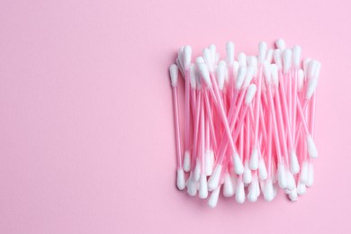 Photo of Heap of cotton buds on pink background, top view. Space for text