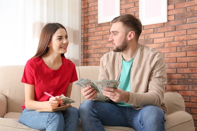 Beautiful young couple with money at home