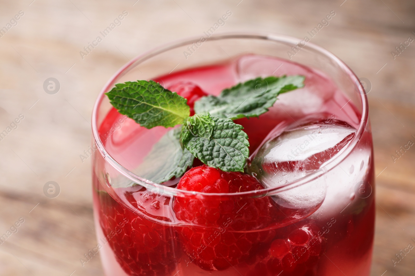 Photo of Glass of refreshing drink with raspberry and mint on table, closeup view