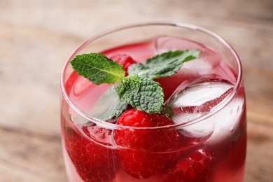 Glass of refreshing drink with raspberry and mint on table, closeup view