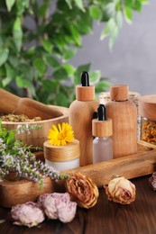 Jar, bottles of essential oils and different herbs on wooden table