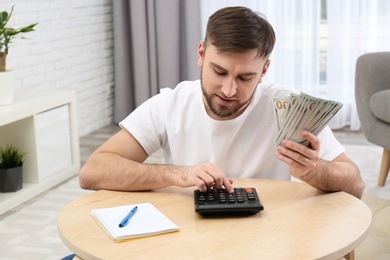 Photo of Happy young man with money at home