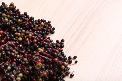Photo of Tasty elderberries (Sambucus) on wooden table, top view. Space for text