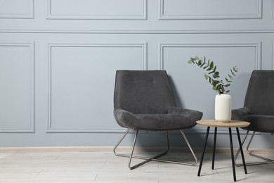 Comfortable armchairs, side table and eucalyptus indoors, space for text