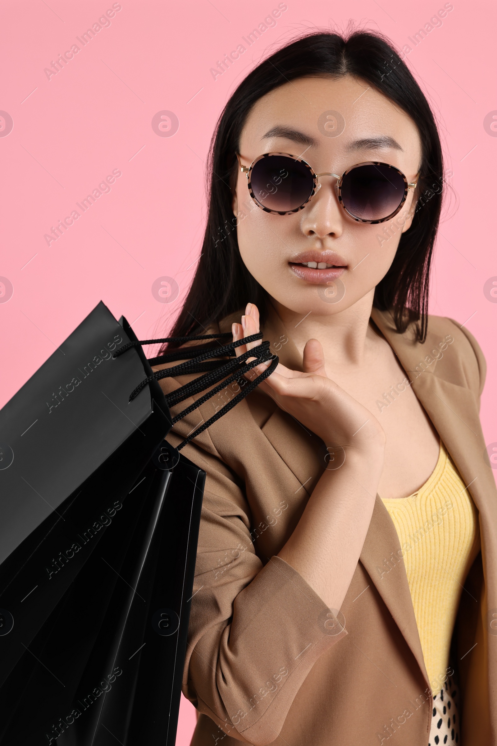 Photo of Beautiful woman with shopping bags on pink background