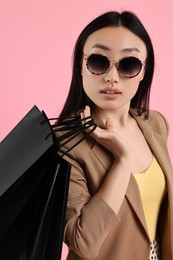 Beautiful woman with shopping bags on pink background