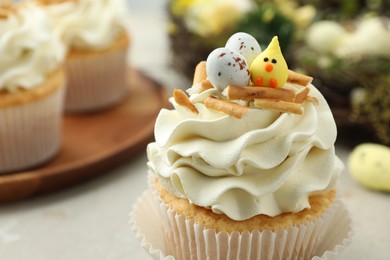 Photo of Tasty Easter cupcakes with vanilla cream on gray table, closeup