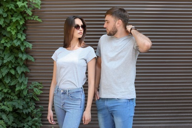 Photo of Young couple wearing gray t-shirts near wall on street.