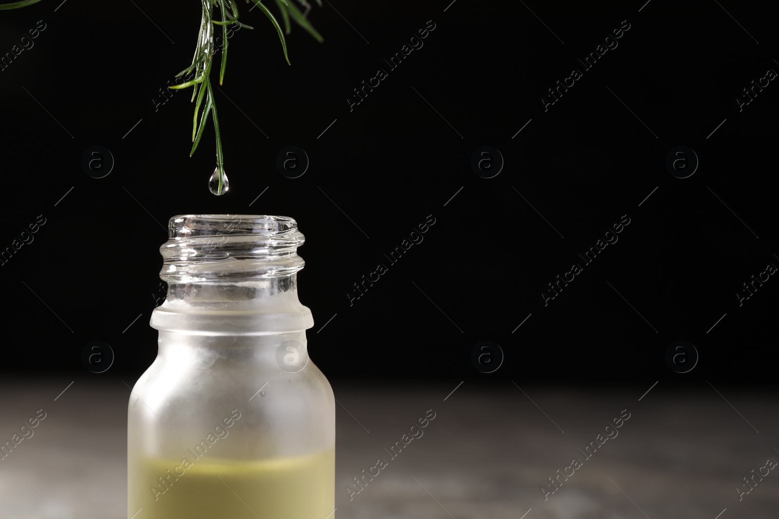Photo of Dripping essential oil from dill into bottle against black background, closeup. Space for text