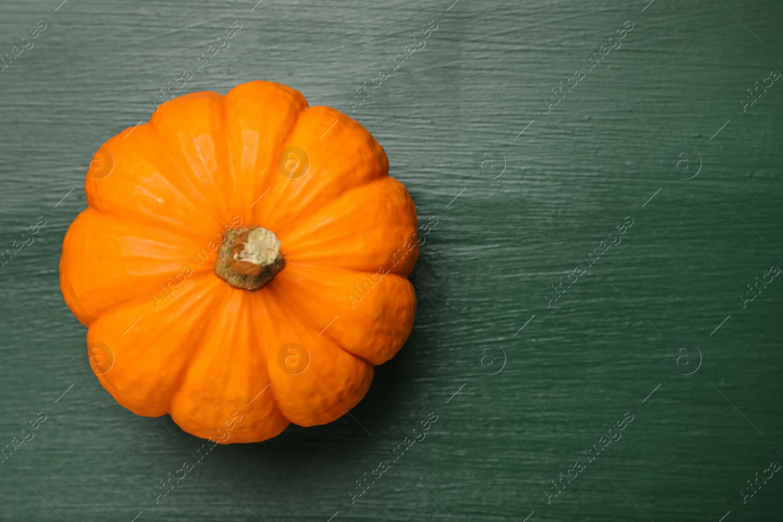 Photo of Fresh ripe pumpkin on green wooden table, top view. Space for text