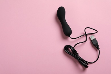 Photo of Black vibrator on pink background, top view with space for text. Sex toy