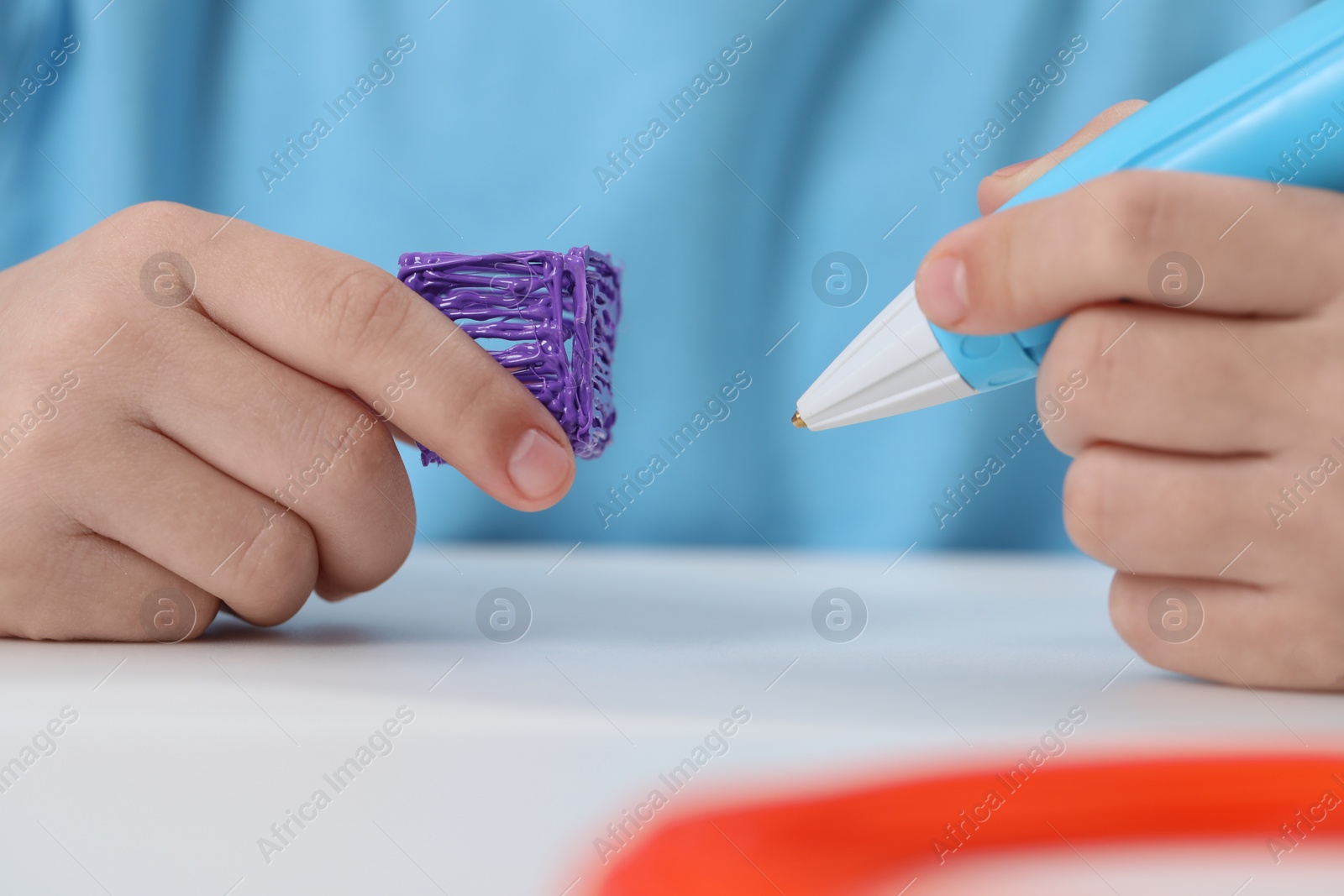 Photo of Girl drawing with stylish 3D pen at white table indoors, closeup