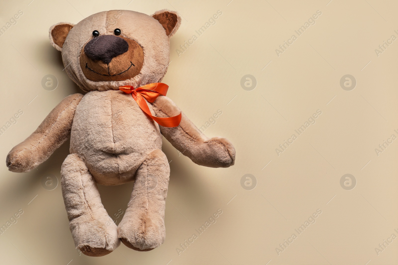 Photo of Cute teddy bear on beige background, top view. Space for text