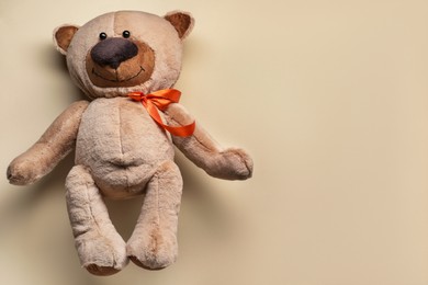 Cute teddy bear on beige background, top view. Space for text