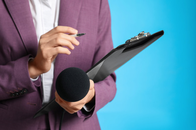 Professional journalist taking notes on light blue background, closeup