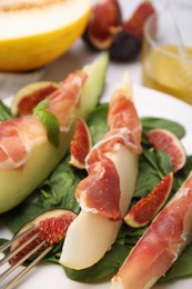 Photo of Tasty melon, jamon and figs served on plate, closeup