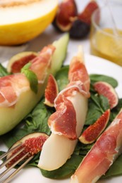 Tasty melon, jamon and figs served on plate, closeup