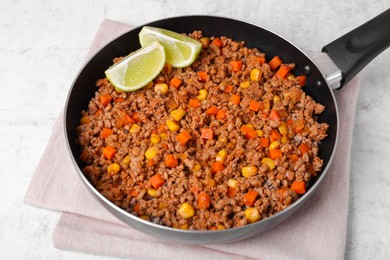 Photo of Fried minced meat, carrot, corn and lime in pan on white textured table