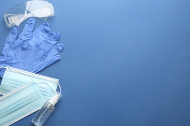 Flat lay composition with medical gloves, masks and hand sanitizer on blue background. Space for text