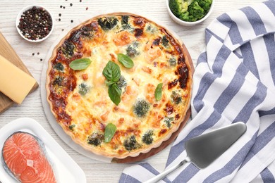 Delicious homemade quiche, ingredients and spatula on table, flat lay